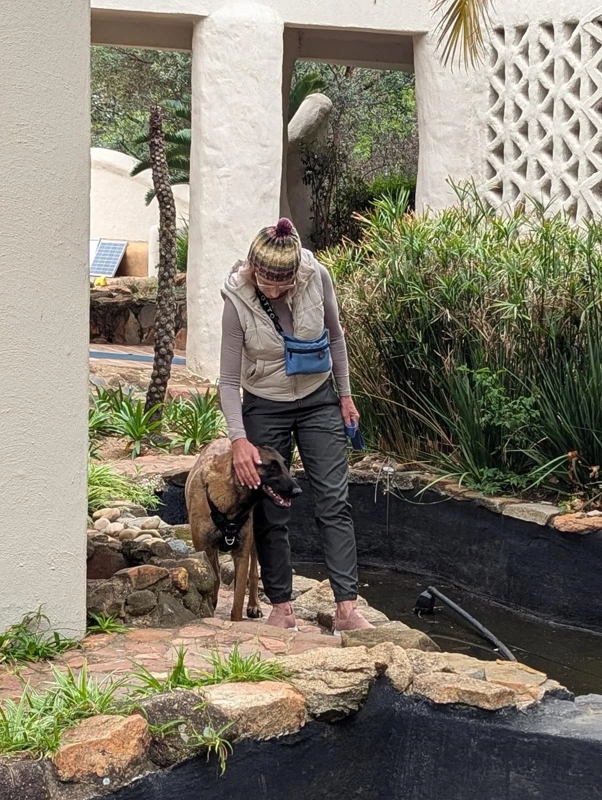 A handler and dog pause together in a garden search area